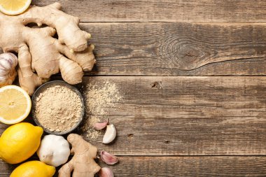 Zencefil kökü, zencefil tozu, sarımsak ve ahşap zemin üzerinde taze limon.