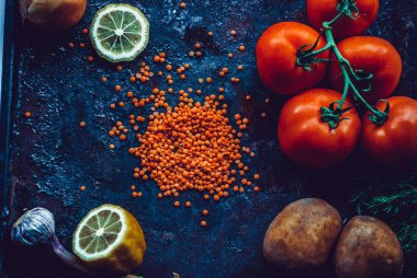 Ev yapımı Türk Mercimek çorba, mercimek, domates, patates, karanlık bir arka plan üzerinde otlar için malzemeler.