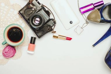 Beyaz ofis resepsiyon masası ile smartphone, vintage fotoğraf makinesi, kahve, kadın ayakkabı ve kozmetik.