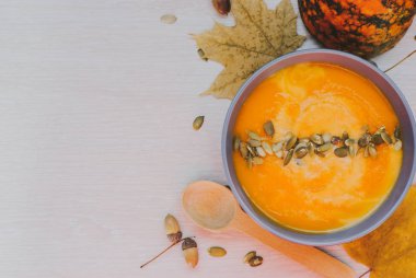 Beyaz ahşap bir masa üzerinde krem ve kabak çekirdeği kabak çorbası. Üstten Görünüm.