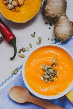 Ahşap arka plan üzerinde krem ve kabak çekirdeği ile kavrulmuş balkabağı çorbası.