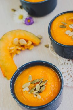 Ahşap arka plan üzerinde kabak çekirdeği ile kavrulmuş balkabağı çorbası.