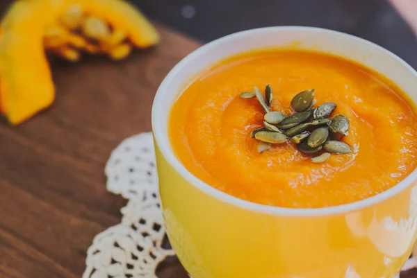 Soupe de citrouille rôtie avec crème et graines de citrouille sur fond en bois . — Photo