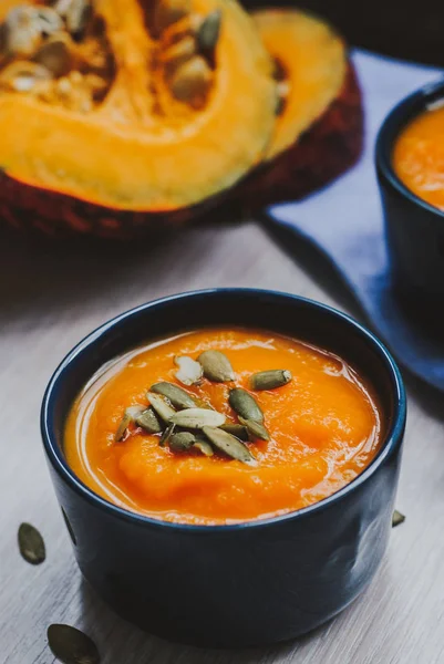 Roasted pumpkin soup with pumpkin seeds on wooden background.