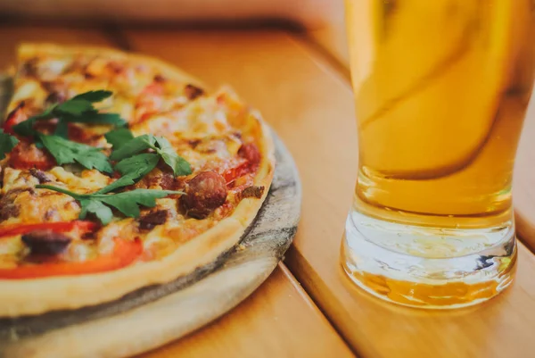 Lezzetli pizza ve bira cam ahşap masaya vardır
