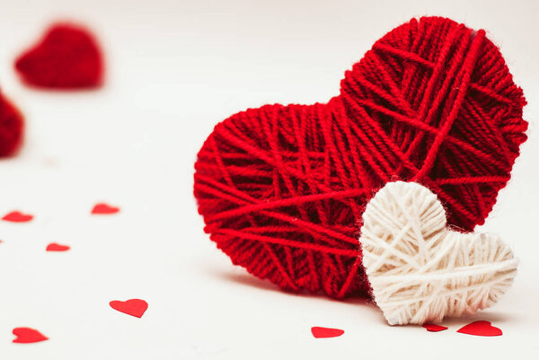 Two red and white clews in shape of heart made from yarn