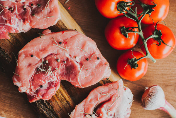 Pieces of raw pork steak with spices and herbs rosemary, thyme, basil, salt and pepper