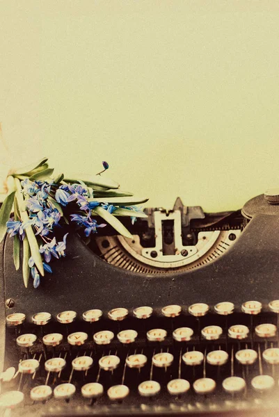 Oude antieke zwart vintage typemachine met blauwe romantische Lentebloemen. — Stockfoto