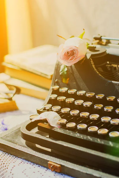 Máquina de escrever vintage com rosa rosa, livros antigos — Fotografia de Stock