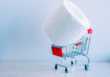 Tüketicilerin koronavirüs paniğinin sembolü olarak alışveriş arabasındaki beyaz tuvalet kağıdı rulosu.