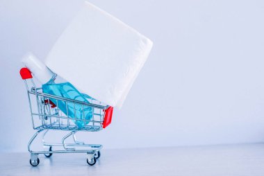 Tüketicilerin koronavirüs paniğinin sembolü olarak alışveriş arabasında beyaz tuvalet kağıdı ve dezenfektan.