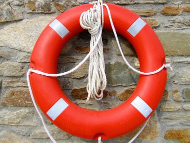 Taştan bir duvar arka planda turuncu ve beyaz lifebuoy yüzükle