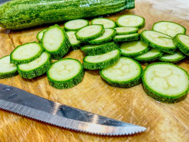 Ahşap zemin üzerinde bıçak olan yeşil kabak dilimlerini kapatın. HDR etkisi.