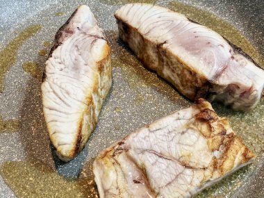 Daha büyük kehribar parçaları pişirmek, bir Akdeniz balığı, gri yapışkan olmayan bir tencerede zeytin yağı ile.