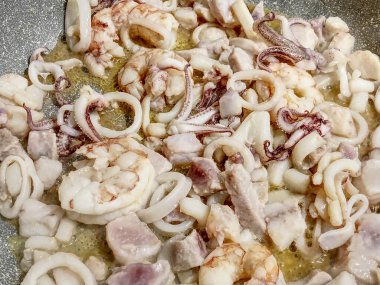 Makarna sosu hazırlamak için zeytinyağında karides, mürekkep balığı ve diğer balıkların karışımını pişiriyorum..