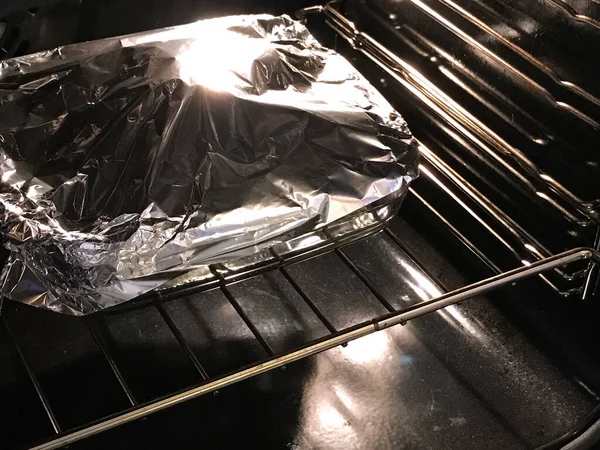 Siyah Elektrikli Fırında Gümüş Alüminyumla Kaplı Bir Fırın Tepsisi — Stok fotoğraf
