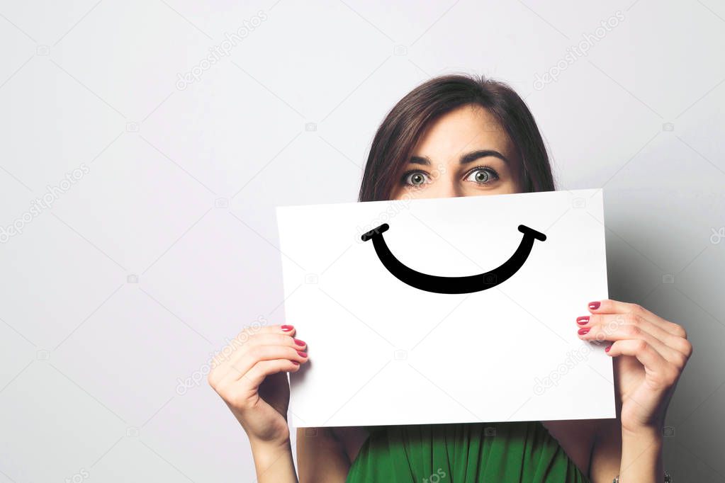 Happy and smiling girl with a smile painted on paper