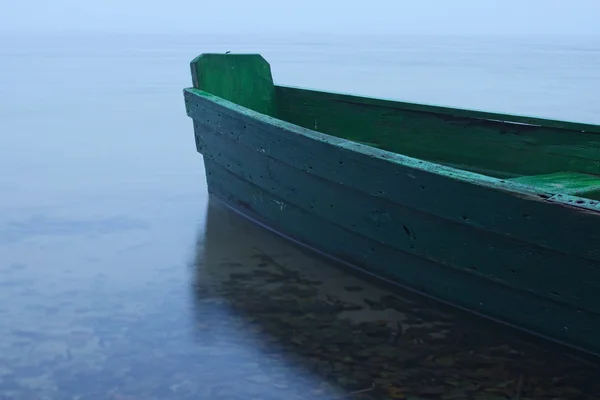 Mattinata nebbiosa sul lago. Barca verde ormeggiata sulla riva — Foto Stock