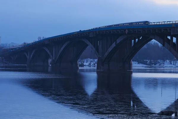 Ледяное утро. Мост метро отражается в воде. Первый поезд метро движется по мосту. Киев. Украина — стоковое фото