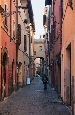 Bir sırt çantası ile yalnız bir turist bir dar uzun cadde boyunca yürür. Roma, İtalya