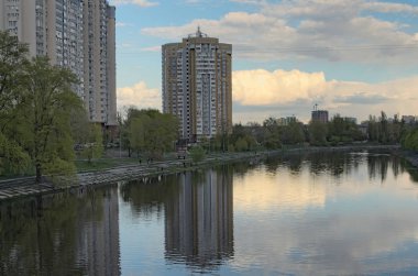 Kalacak yer. Sessiz ve rahat alan Kiev'de Dinyeper Nehri'nin sol tarafında. Çok katlı bina suda yansıtılır. Bulutlu bahar günü. Kiev, Ukrayna