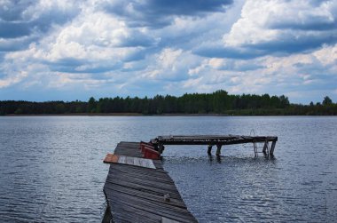 Terk edilmiş göl kıyısında ahşap iskele. Arka plan üzerinde karanlık fırtına bulutları. Volyn bölgesi. Ukrayna
