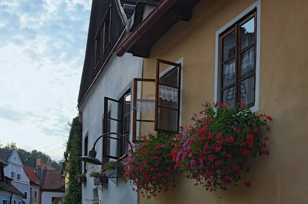 Janelas decoradas com flores vermelhas em caixas de flores durante o pôr do sol de verão. Cidade velha de Cesky Krumlov, República Checa — Fotografia de Stock