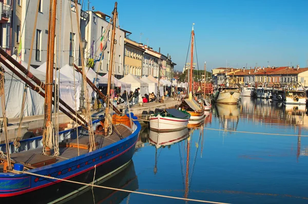 CESENATICO, ITALIA: 01 ENERO 2017- Quioscos Feria de Navidad en el terraplén del canal portuario con los típicos barcos pesqueros del Mar Adriático — Foto de Stock
