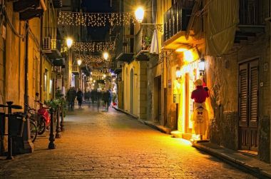 Cefalu, İtalya-Ocak 03, 2017: Noel ışıkları dekorasyon antik dar sokak. İnsanlar yürüyor