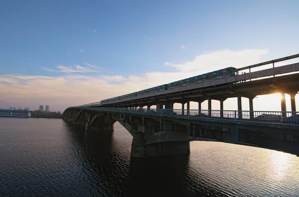 Pittoresca vista sul ponte della metropolitana (metropolitana) sul fiume Dnipro a Kiev, Ucraina. La metropolitana si sta muovendo lungo il ponte. Alba al mattino d'inverno — Foto Stock