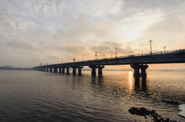 Ismarlayarak Paton'ın Köprüsü kış gündoğumu sırasında Dinyeper Nehri üzerinde. Güneş suya yansıyan. Kiev, Ukrayna. Geniş açı lens ile seçici odak