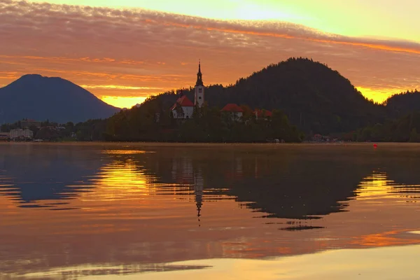 Magické barvy při východu slunce na jezeře Bled. Poutní kostel Nanebevzetí Panny Marie a pohoří se odráží ve vodě. Dramatické nebe a východ slunce. Slavná destinace pro cestování ve Slovinsku — Stock fotografie