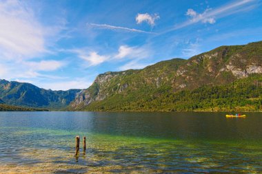 Bohinj Gölü 'nün (Bohinjsko jezero) geniş açılı manzarası ve arka planda manzaralı dağ geçidi. Manzara ve doğa kavramı, güneşli bir gün. Triglav Ulusal Parkı, Slovenya
