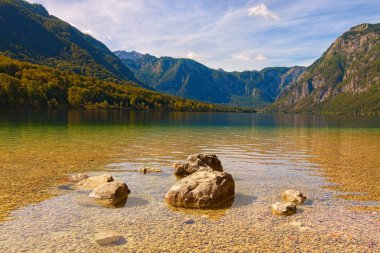 Bohinjsko Jezero Gölü 'nün (Bohinjsko jezero) geniş açılı manzara manzarası, güneşli bir günde renkli ve canlı bir gökyüzüne karşı manzaralı dağ sırasıdır. Triglav Ulusal Parkı, Slovenya. Manzara ve doğa kavramı