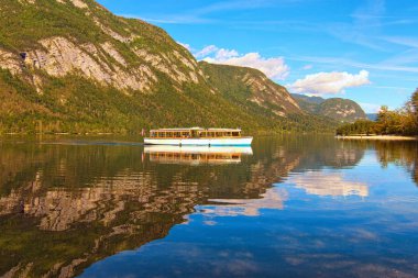 Bohinj Gölü 'ndeki eski turistik tekne. Bohinj Gölü 'nün turkuaz suya yansıyan panoramik manzarası. Romantik ve huzurlu bir sahne. Bohinj Gölü, Triglav Ulusal Parkı, Slovenya