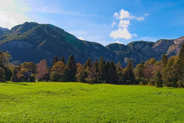 Majestosa paisagem natural de belo vale com alguns edifícios na floresta e pitoresca cordilheira no fundo. Dia de outono ensolarado. Eslovénia — Fotografia de Stock