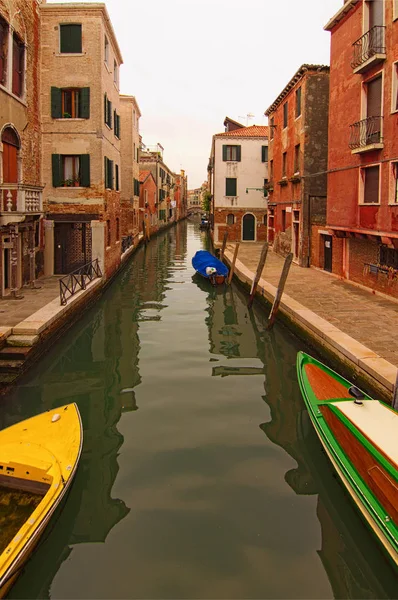 Amplia vista panorámica de la calle típica de Venecia. Parte no turística de la ciudad. Antiguos edificios reflejados en aguas turquesas de estrecho canal. Barcos amarrados al lado del canal. Venecia, Italia — Foto de Stock
