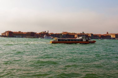 Vaporetto, Venedik halk su otobüsüdür. Seyahat ve turizm konsepti. Venedik gölü manzarası ve arka planda binalar. Sonbahar güneşli bir gün. Venedik, İtalya