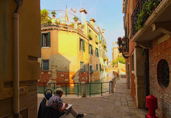 Venecia, Italia-28 de septiembre de 2019: Un artista dibujando un paisaje de colorido edificio con canal en el soleado día de otoño. Famoso lugar turístico y destino turístico romántico — Foto de Stock