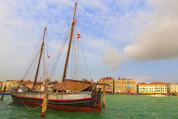 Barco de madera de dos mástiles amarrado en Venecia cerca de Punta della Dogana. Antiguo velero al aire libre en el muelle del canal. Edificios coloridos en el fondo. Día soleado de otoño en Venecia, Italia — Foto de Stock