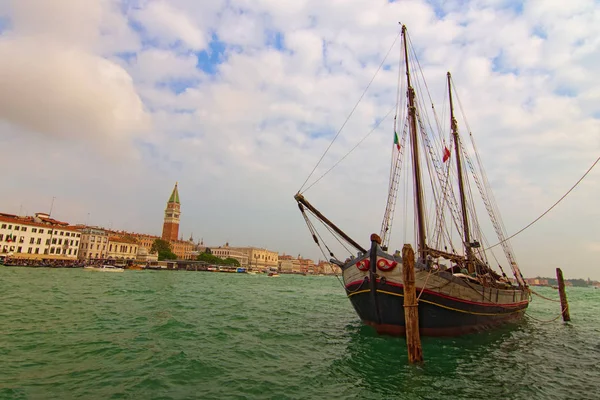 Antiguo barco de madera de dos mástiles amarrado en Venecia cerca de Punta della Dogana. Antiguo velero al aire libre en el muelle del canal. Edificios coloridos en el fondo. Día soleado de otoño en Venecia, Italia — Foto de Stock