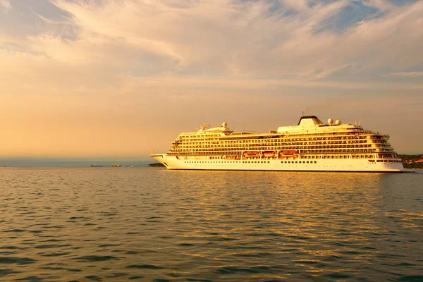 Huge luxury cruise ship glides out of the port of Koper during magic sunset. Colorful vibrant sky. Travel and tourism concept. Koper, Slovenia