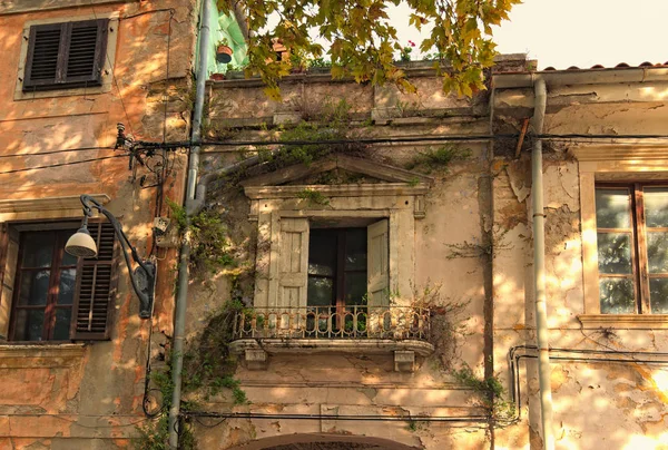 Clásica vista panorámica de la fachada del edificio abandonado. Ventanas viejas con persianas de madera. Las malas hierbas crecen en la pared. Piran, Eslovenia — Foto de Stock