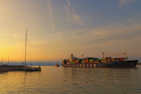 Koper, Slovenia-27. september 2019: Tugboat trekker store containerskip ut av havnen. Import, eksport og forretningslogikk. Internasjonal sjøtransport. Vakkert landskap under solnedgang – stockfoto