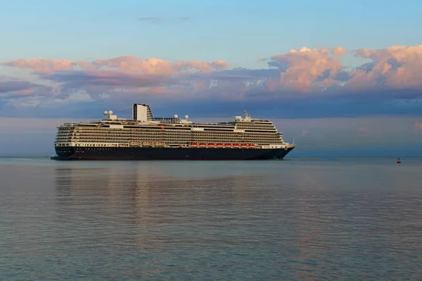 Vista panorâmica da manhã de um enorme navio de cruzeiro de luxo no horizonte. Ele desliza para o porto de Koper durante o nascer do sol mágico. Céu vibrante colorido. Transporte internacional de água. Koper, Eslovénia — Fotografia de Stock