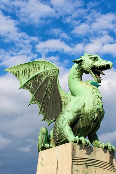 Green Dragon is main symbol of Ljubljana. It is one of four statues that adorn the famous Dragon bridge (Zmajski most). Travel and tourism concept. Vibrant sky in the background. Ljubljana, Slovenia