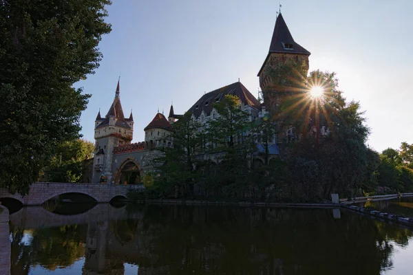 Weitwinkel-Landschaft Ansicht der Burg Vajdahunyad. Stadtpark von Budapest, Ungarn. Sonnenstrahlen leuchten, heller Blitz. malerische Herbstlandschaft. Beliebtes Reiseziel in der Stadt — Stockfoto