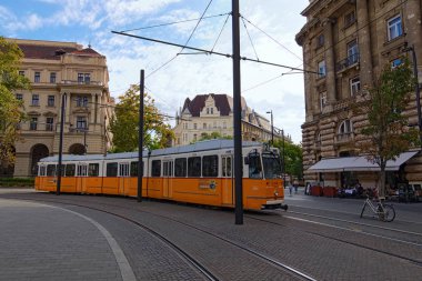 Budapest, Hungary-October 01, 2019: Typical yellow vintage tram turn left. Famous lane 2 is one of the major tourist attraction of the Budapest. Colorful ancient buildings in the background