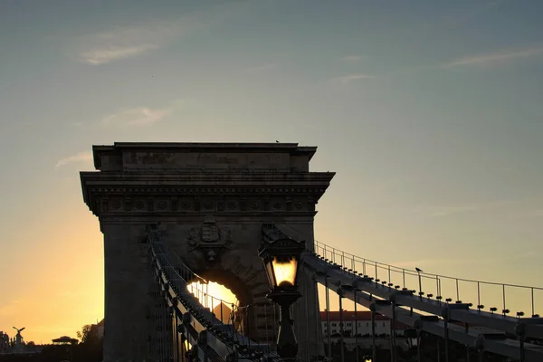 Niesamowity widok sylwetki Chain Bridge podczas jesiennego zachodu słońca. Piękna starożytna latarnia. Romantyczna i spokojna scena. Panoramiczne dramatyczne niebo zachodu słońca. Budapeszt, Węgry — Zdjęcie stockowe