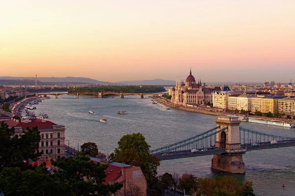 Őszi naplemente Budapesten. Légi kilátás a városra. Hidak a Duna felett, festői töltés a középkori Parlamenttel. Híres turisztikai hely és úti cél Európában — Stock Fotó